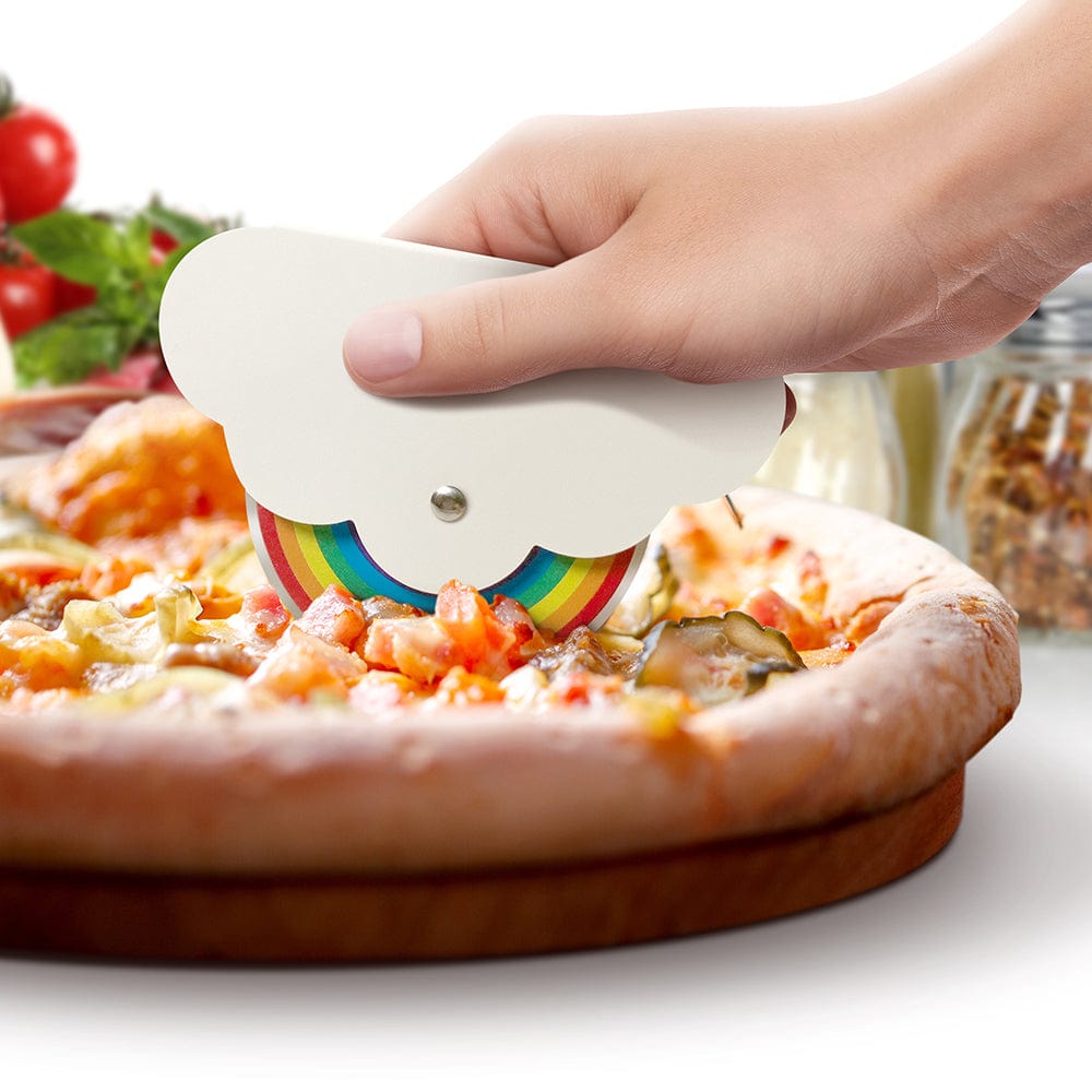 A woman's hand is cutting a pizza with a pizza cutter that looks like a cloud and rainbow. The handle is a cloud and the stainless steel blade is printed with a seven color rainbow